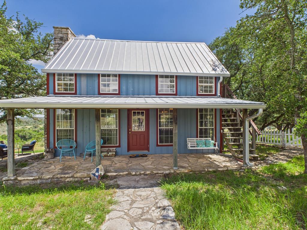 a view of a white house with a yard potted plants and large tree
