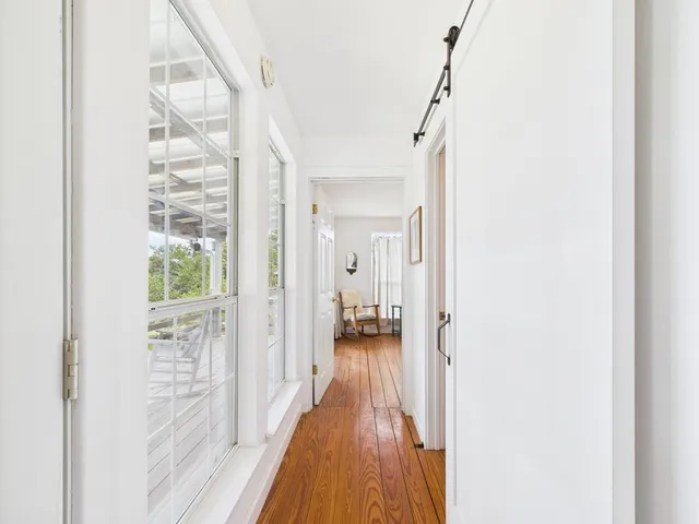 a view of a hallway with wooden floor and a bathroom