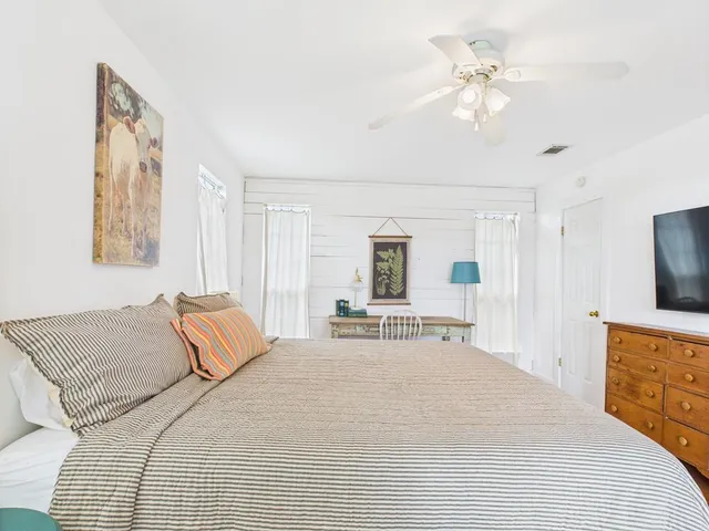 a spacious bedroom with a bed a chandelier and a flat screen television
