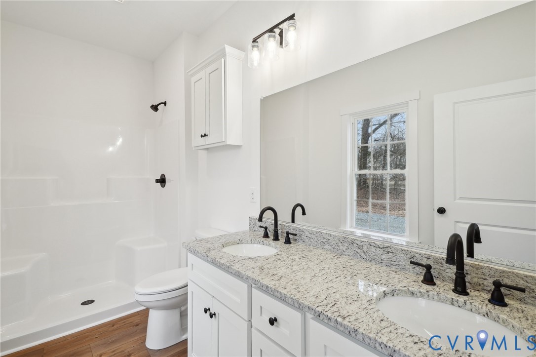 3520 Clintwood Road Midlothian, VA 23112 - Photo 20 of 32 a bathroom with a granite countertop sink toilet a large mirror a bathtub and shower
