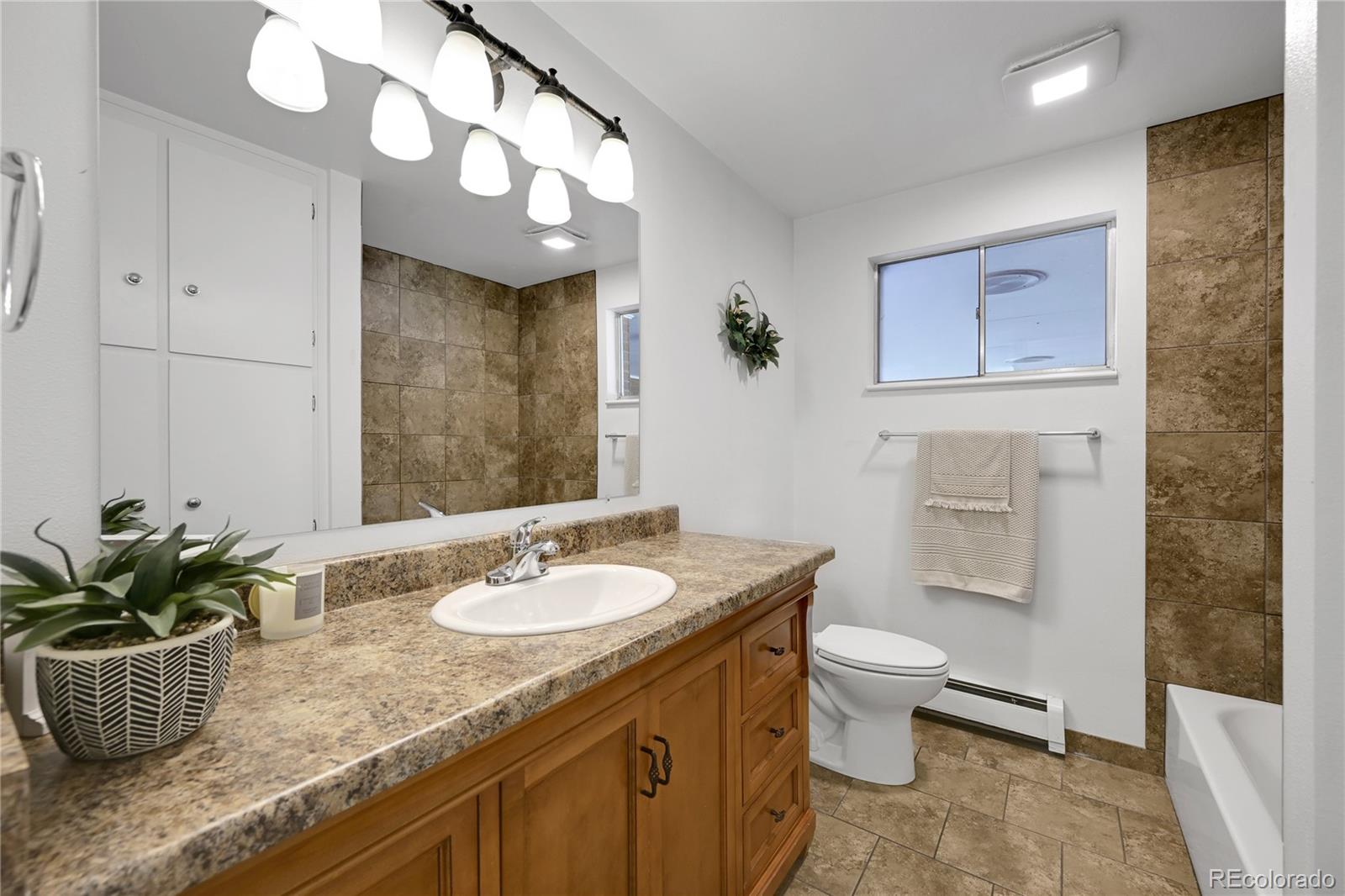 3709 Allison Street Wheat Ridge, CO 80033 - Photo 15 of 44 a bathroom with a granite countertop sink a mirror and a toilet