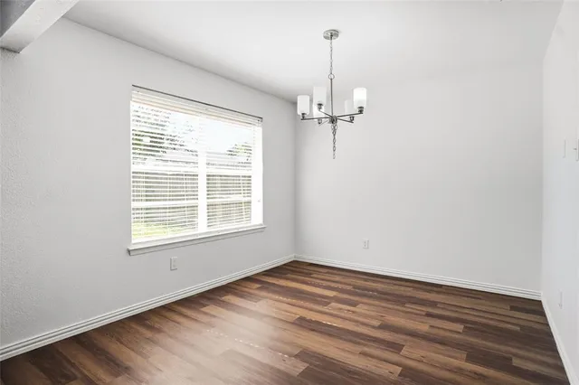 a view of empty room with wooden floor fan and window