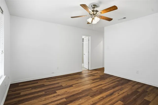an empty room with wooden floor and a ceiling fan