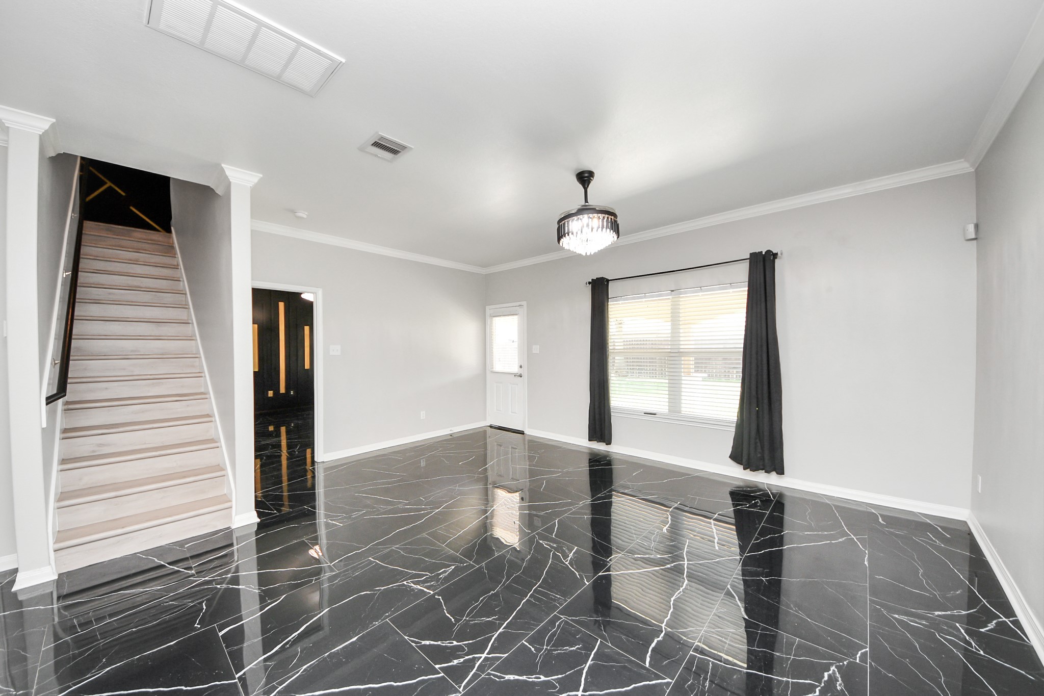 6931 Primrose Road Baytown, TX 77521 - Photo 28 of 50 Bright living room with striking marble-look tile flooring, crown molding, and direct access to the backyard, with stairs leading to the upper level.