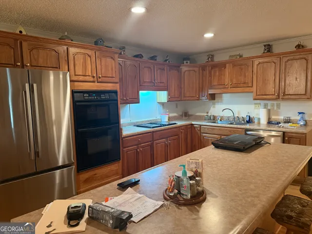 a kitchen with kitchen island a counter top space a sink stainless steel appliances and cabinets