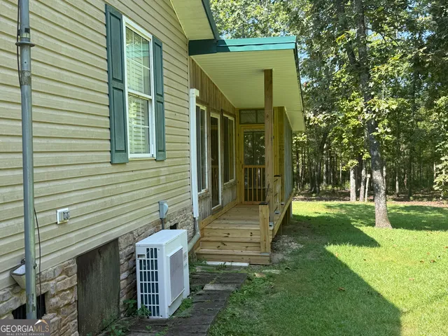 a backyard of a house with table and chairs under an umbrella