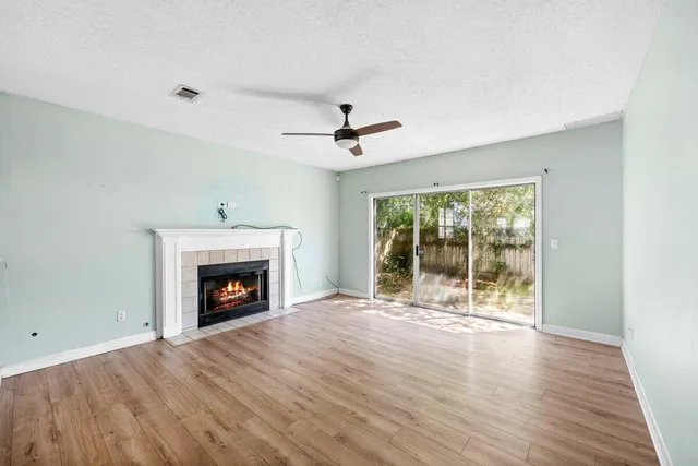 a view of an empty room with wooden floor fireplace and a window