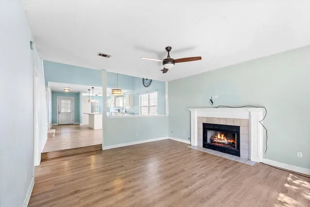 a view of an empty room with wooden floor fireplace and a window