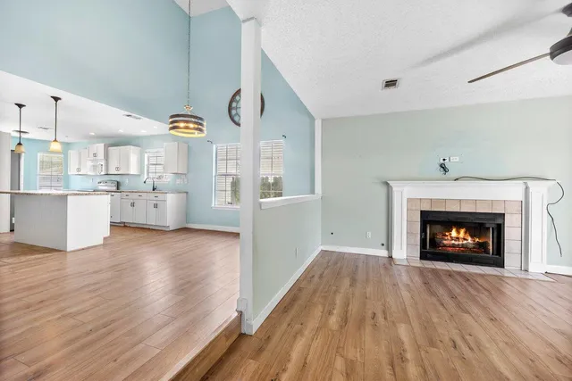a view of a kitchen and an empty room with wooden floor