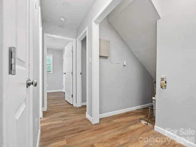 a view of a hallway with wooden floor and a bathroom