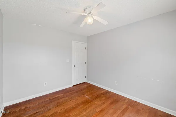 a view of a big room with wooden floor and a ceiling fan
