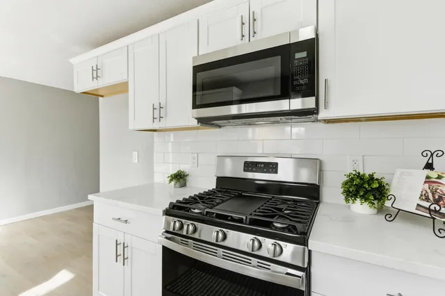 a kitchen with stainless steel appliances a white stove top oven and cabinets