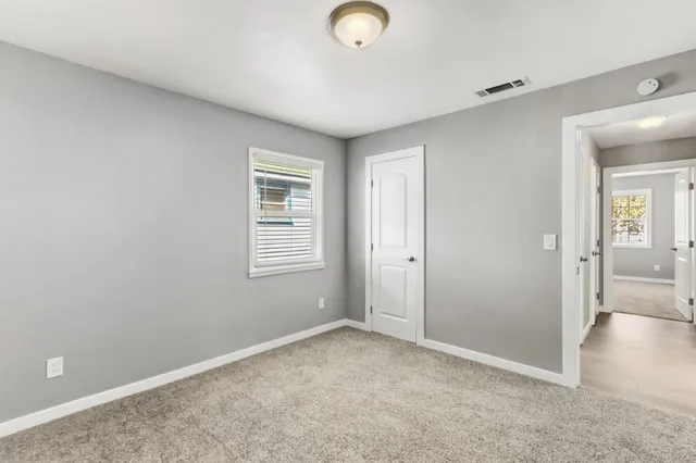 an empty room with windows and a chandelier fan