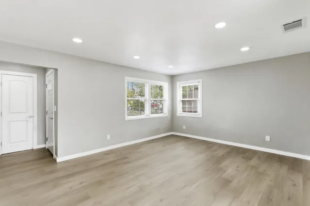 a view of an empty room with wooden floor and a window
