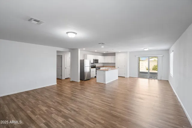 a view of an empty room with window and wooden floor
