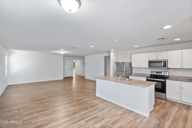 a view of kitchen with kitchen island stainless steel appliances a sink and a stove