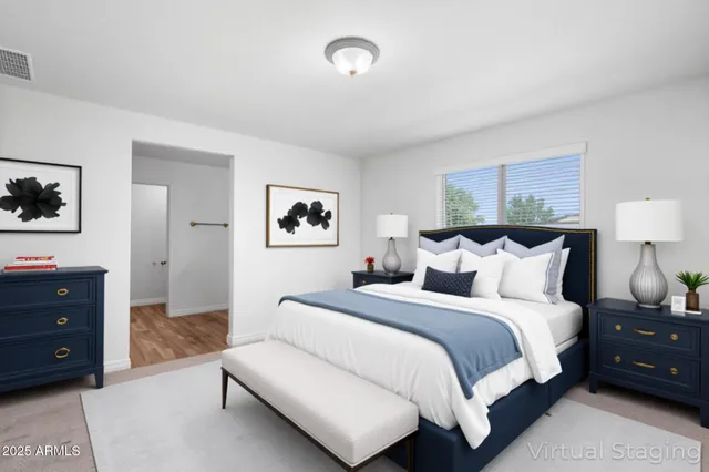 a spacious bedroom with a bed and a lamp on dresser