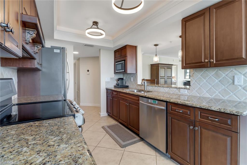 25 Bluebill Avenue, Unit A906 Naples, FL 34108 - Photo 14 of 40 a large kitchen with stainless steel appliances granite countertop a sink and cabinets