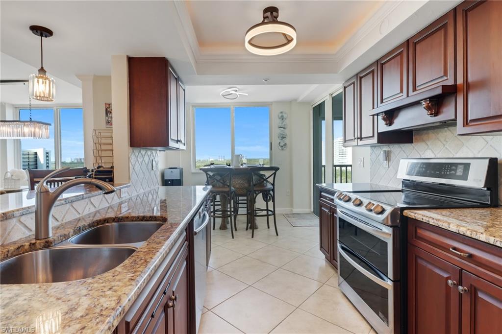 25 Bluebill Avenue, Unit A906 Naples, FL 34108 - Photo 16 of 40 a kitchen with stainless steel appliances granite countertop a sink a stove and a refrigerator