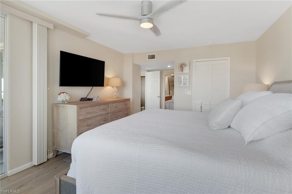 25 Bluebill Avenue, Unit A906 Naples, FL 34108 - Photo 22 of 40 a bedroom with a bed tv and a chandelier