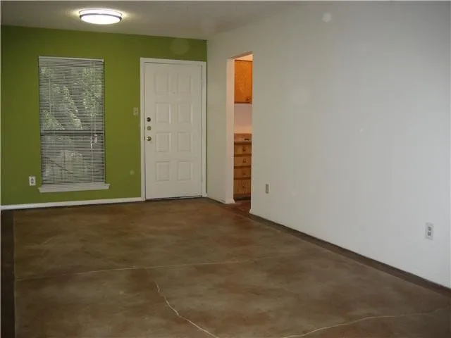 an empty room with chandelier fan and windows