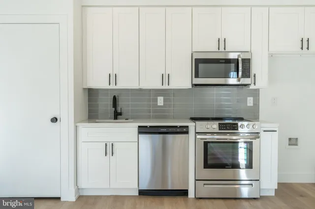 a kitchen with white cabinets and stainless steel appliances