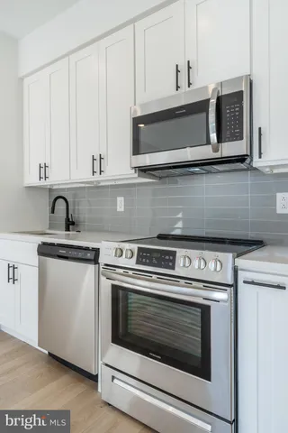a kitchen with granite countertop white cabinets and stainless steel appliances