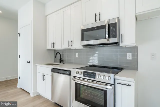 a kitchen with stainless steel appliances granite countertop white cabinets a microwave oven and a sink
