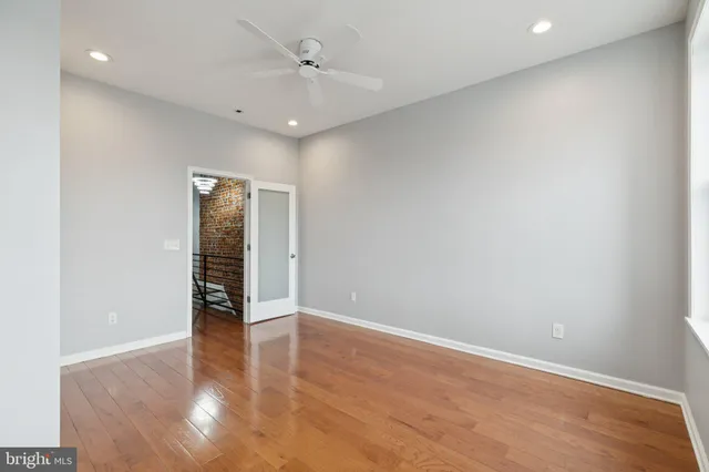 an empty room with wooden floor and a ceiling fan