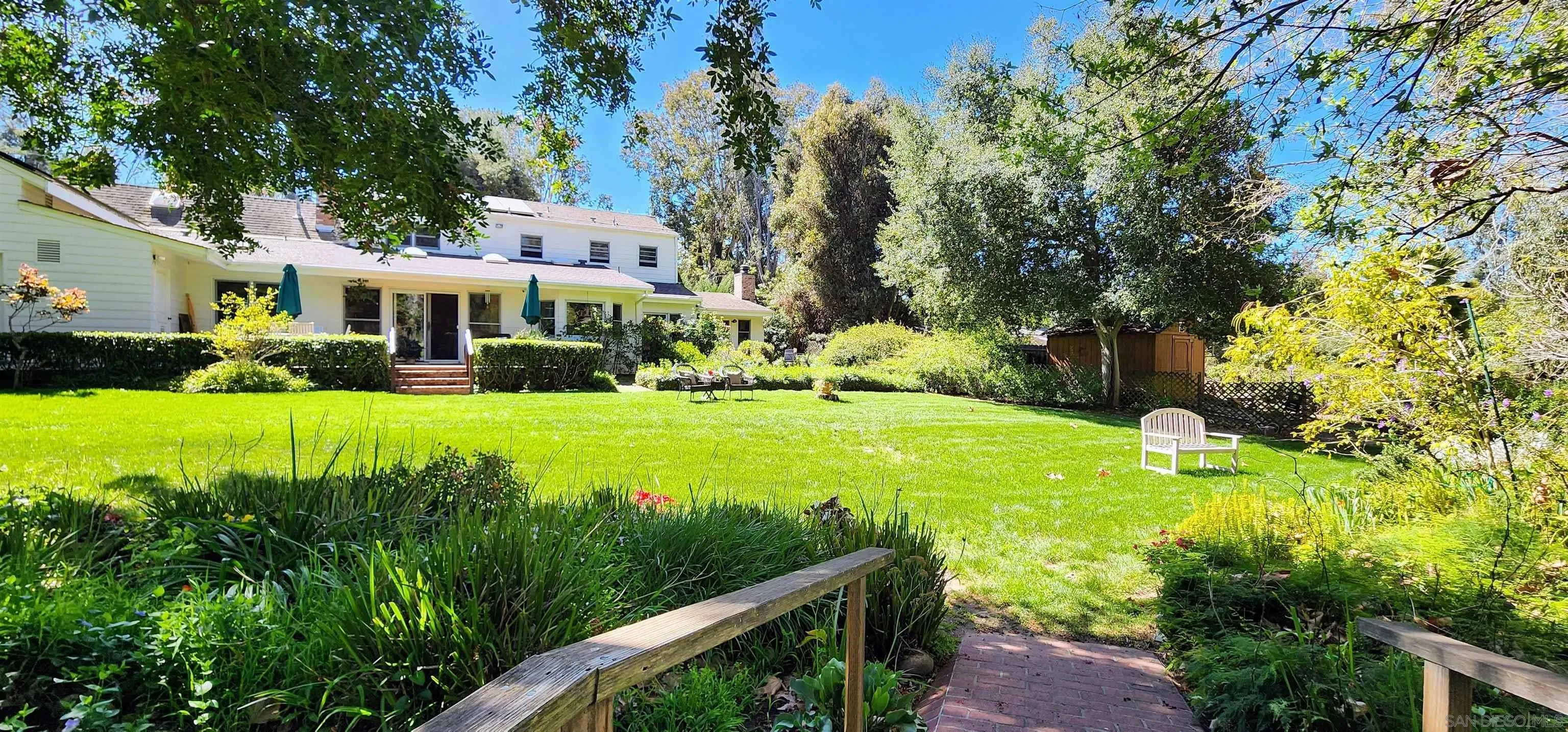 a view of a house with a big yard plants and large trees