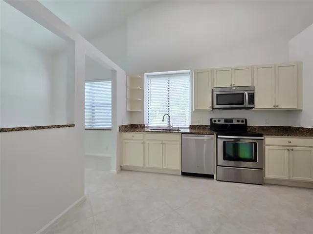 a kitchen with granite countertop a stove a sink and a microwave