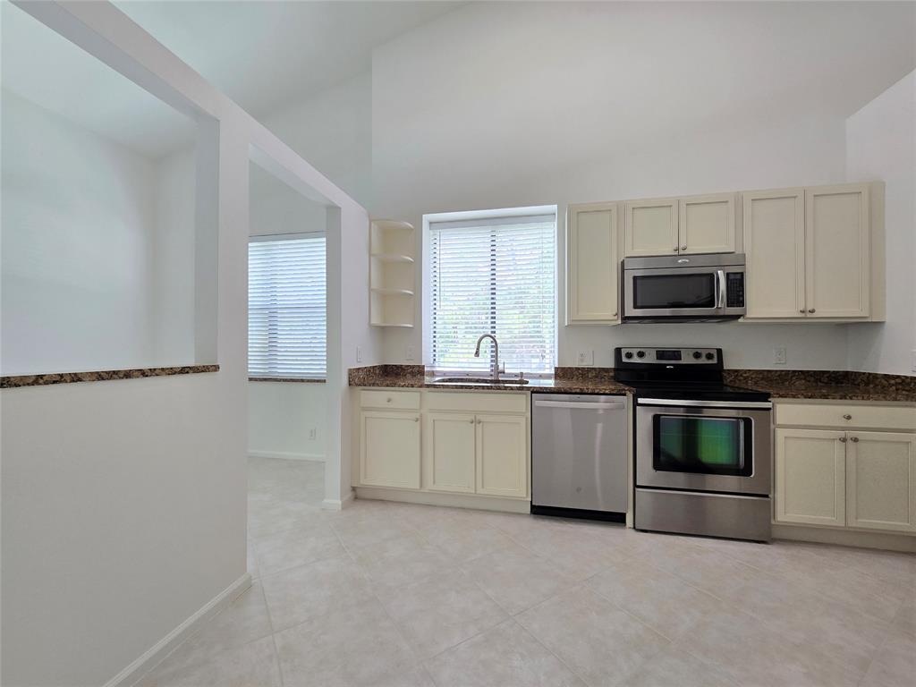 5800 Coach House Circle, Unit D Boca Raton, FL 33486 - Photo 10 of 23 a kitchen with granite countertop a stove a sink and a microwave