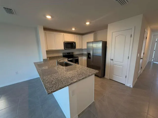 a kitchen with stainless steel appliances granite countertop a refrigerator a stove and a sink