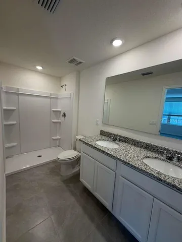 a bathroom with a granite countertop sink mirror and toilet