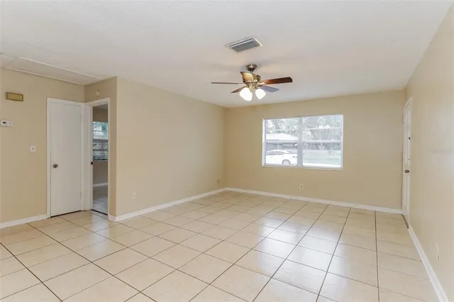 an empty room with windows and chandelier fan