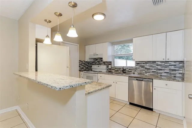 a kitchen with granite countertop a sink and white cabinets