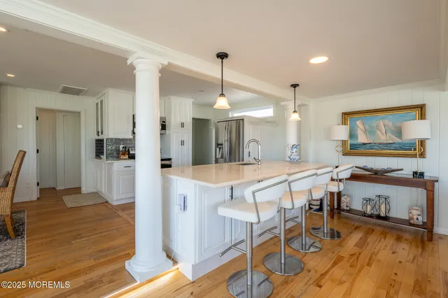 a dining hall with stainless steel appliances granite countertop furniture wooden floor and a view of kitchen