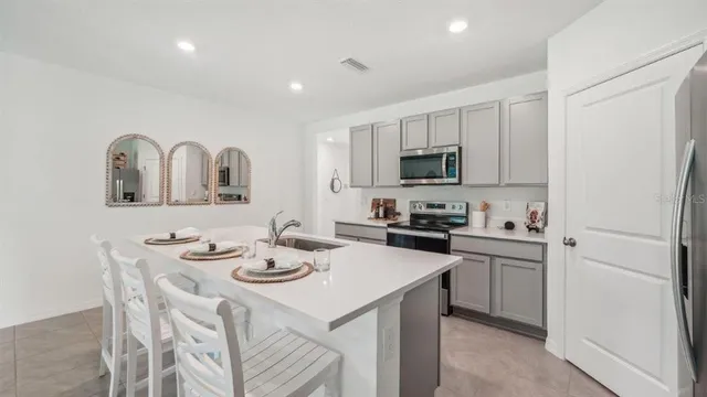 a kitchen with stainless steel appliances granite countertop a sink a stove a refrigerator cabinets and a dining table with wooden floor