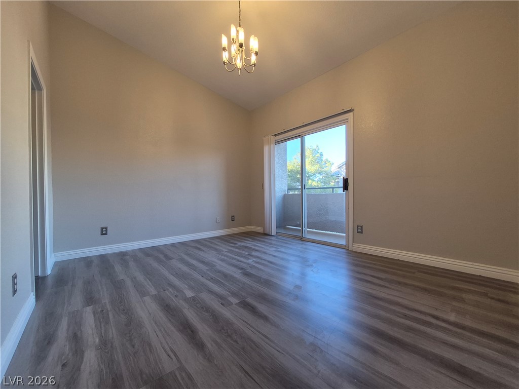 2053 Quarry Ridge Street, Unit 201 Las Vegas, NV 89117 - Photo 5 of 21 Laminate flooring extends into a spacious living area with vaulted ceilings and outdoor access.