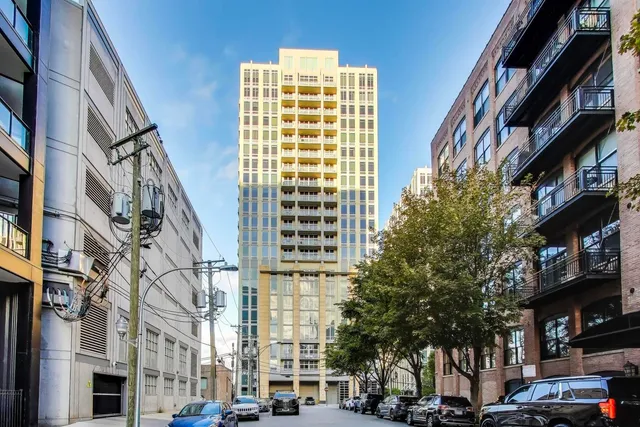 a front view of a building with lot of cars and trees