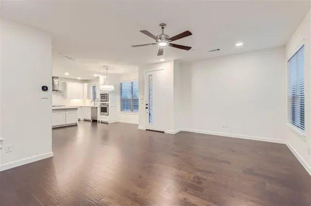 a view of an empty room with a window and wooden floor