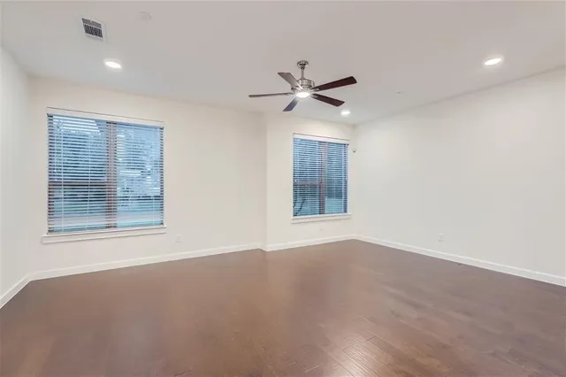 a view of an empty room with a window and wooden floor