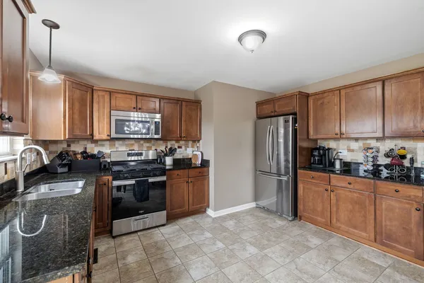 a kitchen with stainless steel appliances granite countertop a stove top oven a sink dishwasher a refrigerator and cabinets with wooden floor
