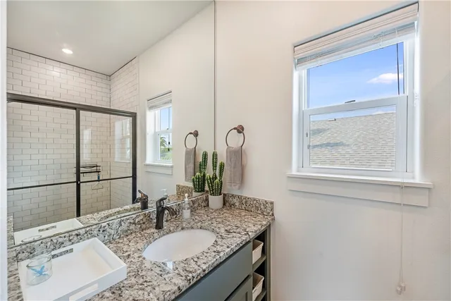 a bathroom with a granite countertop sink a mirror and a shower