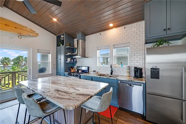 a kitchen with granite countertop a table chairs stove refrigerator and cabinets