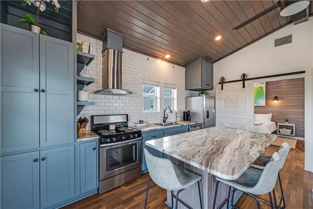 a kitchen with granite countertop a stove chairs and refrigerator