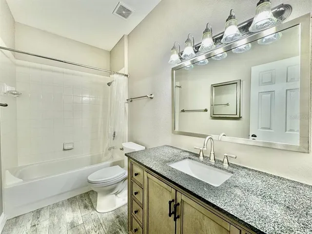 a bathroom with a granite countertop shower a sink and a mirror