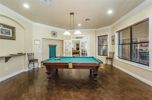 a living room with furniture pool table and a wooden floor