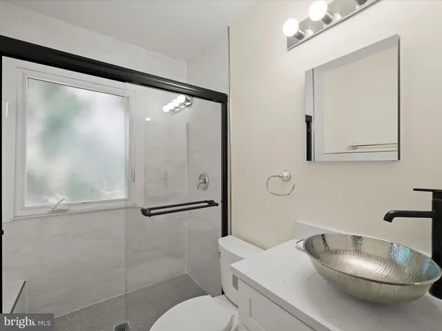 a bathroom with a granite countertop sink mirror vanity and toilet