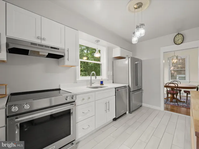 a kitchen with stainless steel appliances granite countertop a stove a refrigerator and a white cabinets
